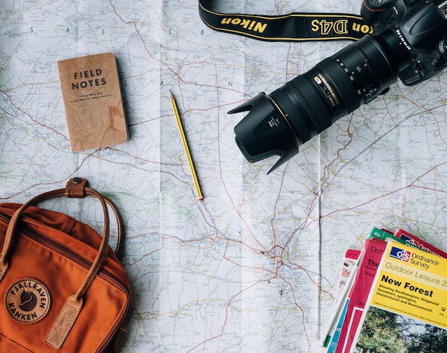 Foto de mapa con mochila de viaje, cuaderno de notas, cámara de fotos y guía de viaje por encima
